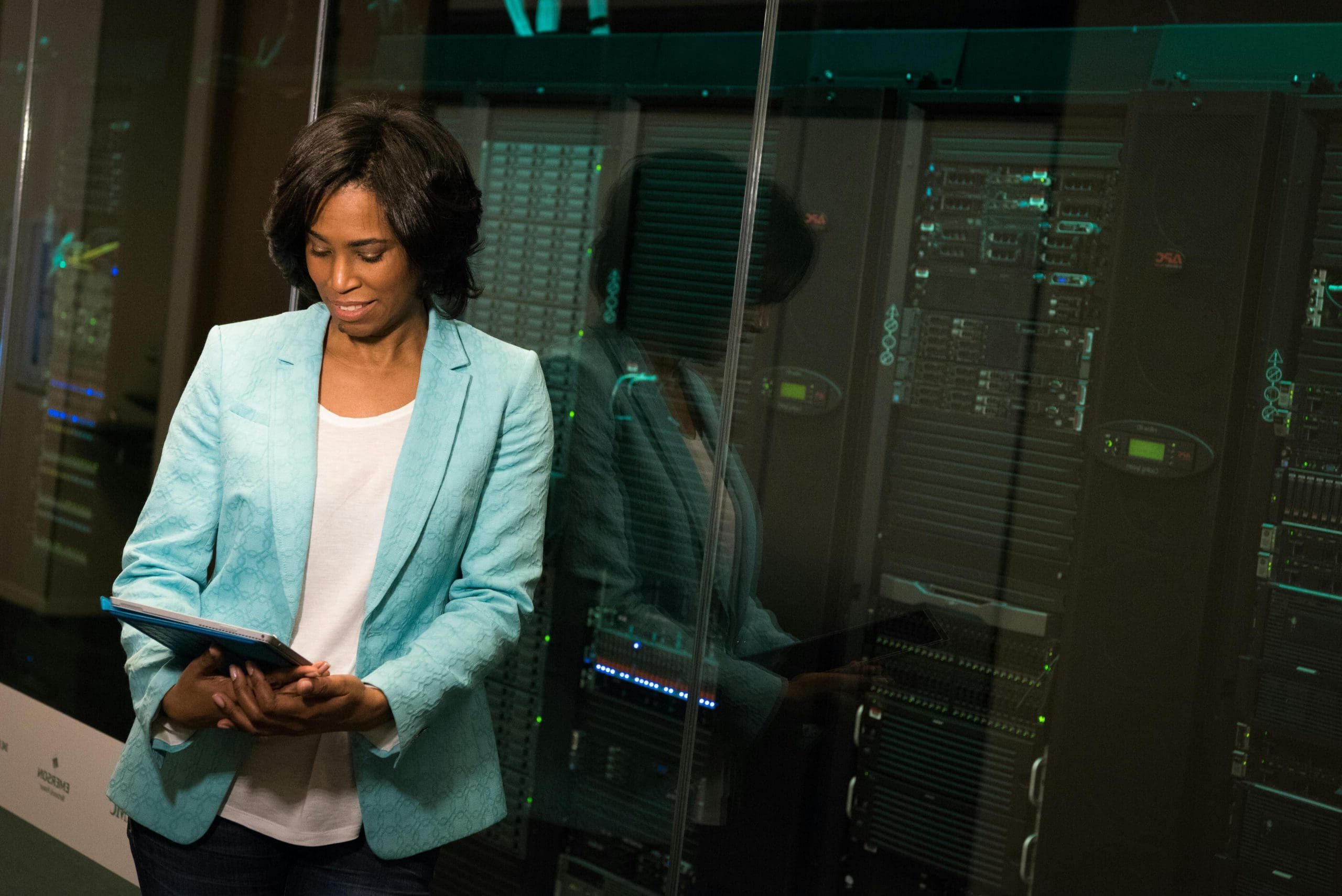 Woman looking at an ipad while standing in front of servers. Photo by Christina Morillo: https://www.pexels.com/photo/software-engineer-looking-at-an-ipad-1181335/